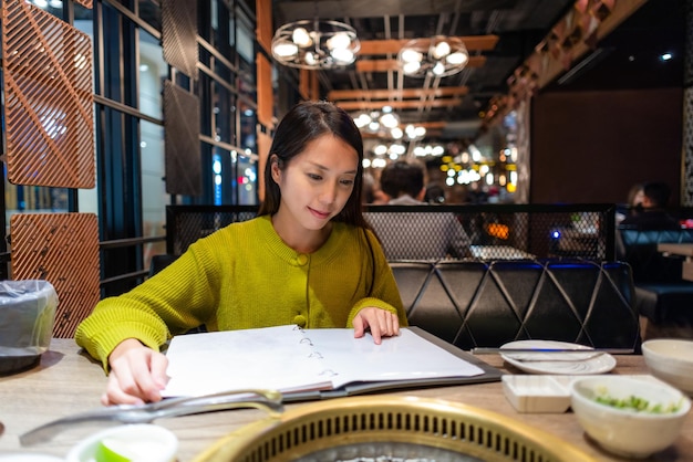 Foto mujer mira el menú del restaurante