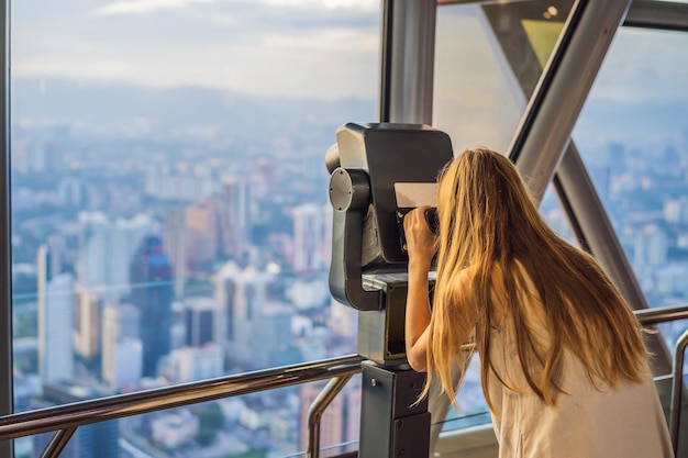 Mujer mira el paisaje urbano de Kuala Lumpur Vista panorámica del horizonte de la ciudad de Kuala Lumpur por la noche en el edificio de rascacielos al atardecer en Malasia