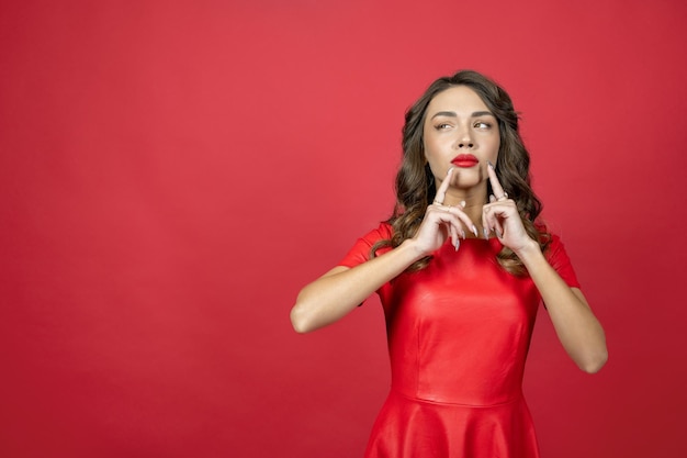 La mujer mira pensativamente sobre un fondo rojo.