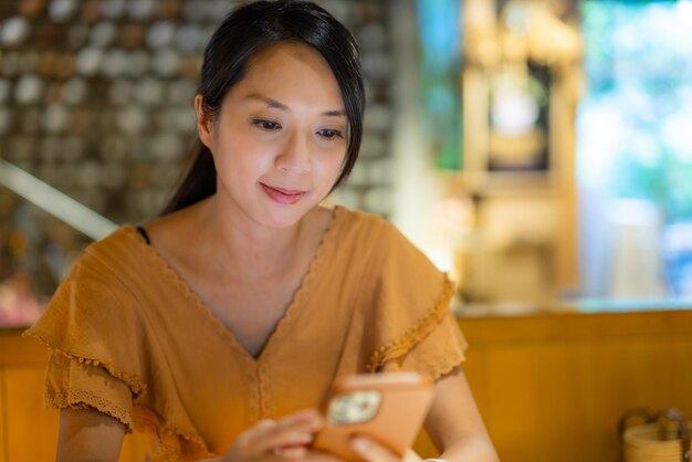 La mujer mira el teléfono inteligente dentro del restaurante