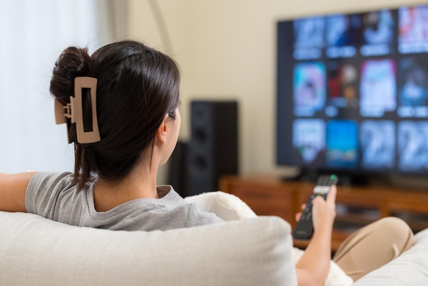 La mujer mira la televisión en casa.