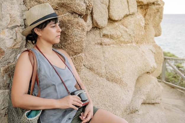 Mujer mirando al infinito frente al mar con una cámara en sus manos