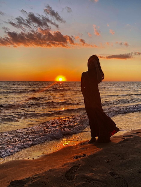 Mujer mirando al mar contra el cielo al atardecer | Foto Premium