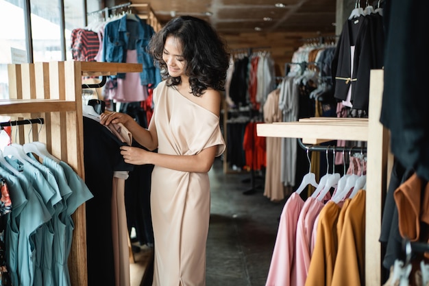 Mujer mirando algo de ropa en la tienda boutique de moda