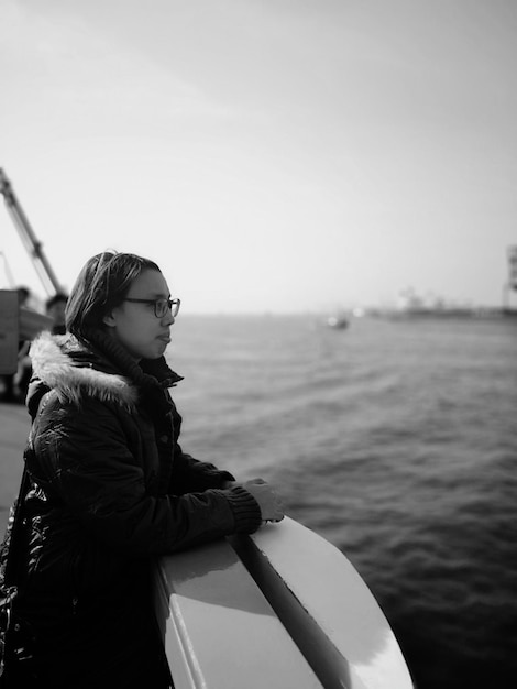 Mujer mirando un barco en el mar contra el cielo