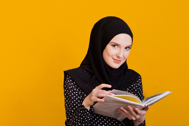 Mujer mirando a cámara con libro en mano sobre superficie