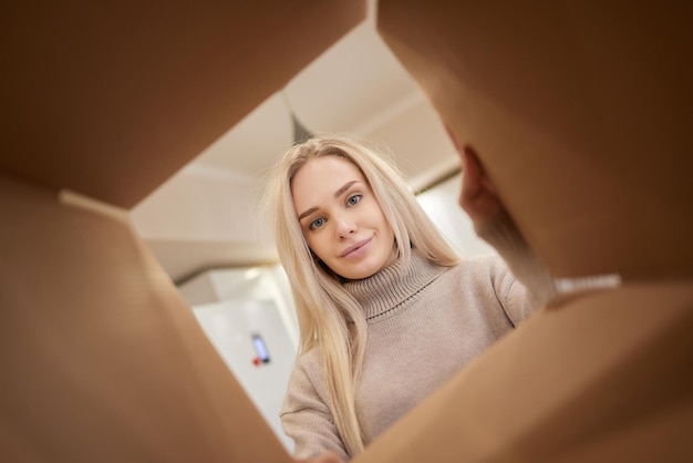 Mujer mirando a la cámara a través de una caja de cartón