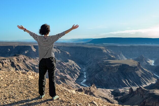 Foto mujer mirando el cañón del río fish en namibia desde el punto de vista de una turista que viaja por áfrica