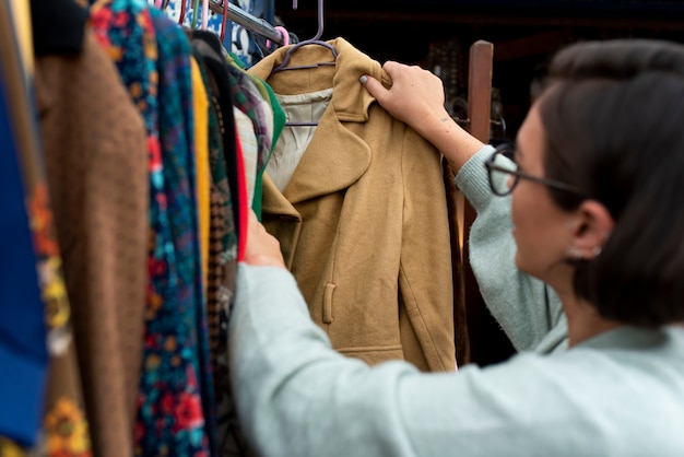 Foto mujer mirando chaqueta en el mercado de segunda mano