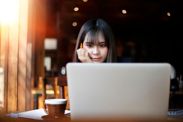 Mujer mirando la computadora portátil en la mesa en una cafetería