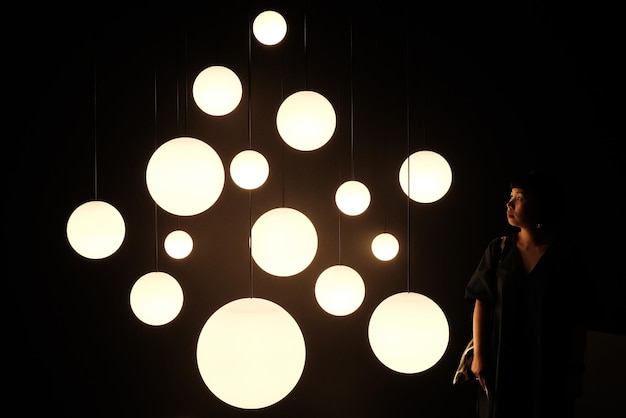 Mujer mirando esferas iluminadas en la oscuridad