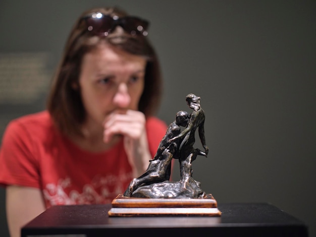 Foto una mujer mirando la estatua en la exposición.