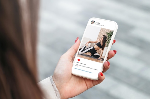 Mujer mirando la foto de una hermosa modelo haciendo yoga en el teléfono móvil