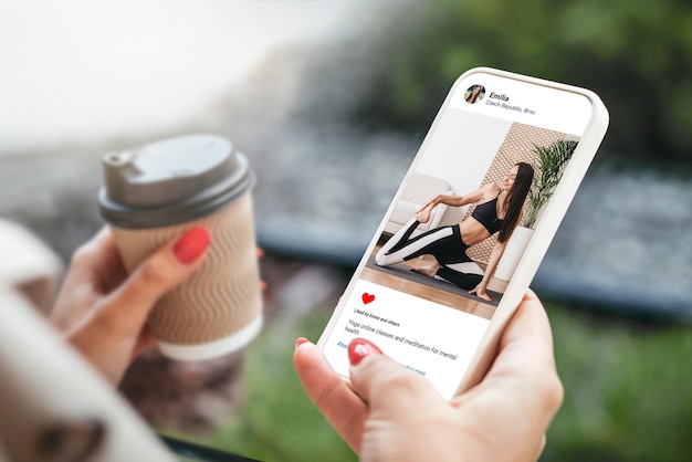 Mujer mirando la foto de hermosas modelos haciendo yoga en el teléfono móvil