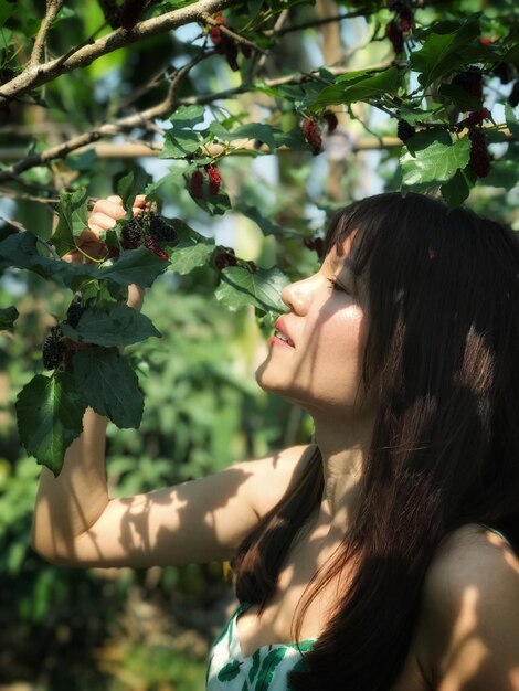 Foto mujer mirando frutas colgando en el árbol