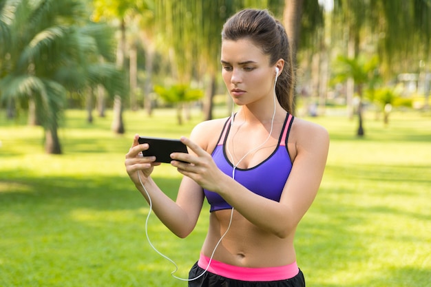 Mujer mirando en línea una lección de fitness durante su entrenamiento en el parque