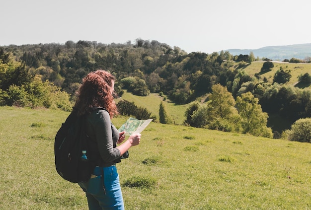 Foto mujer mirando el mapa mientras está de pie en el campo