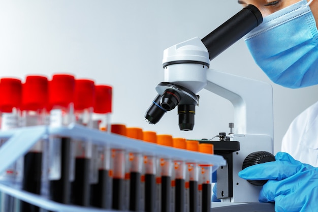 Mujer mirando en microscopio en laboratorio