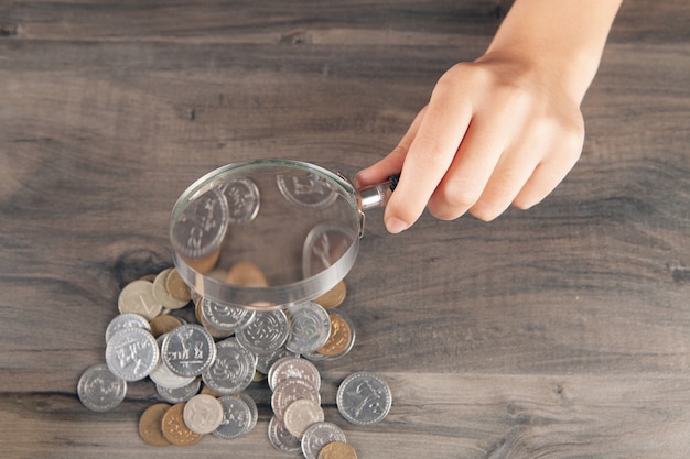 Mujer mirando monedas con lupa