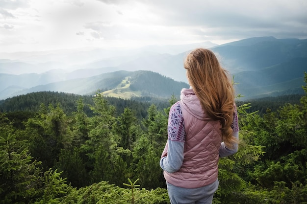 Mujer mirando nublado, paisaje montañoso y sintiendo libertad durante el viaje