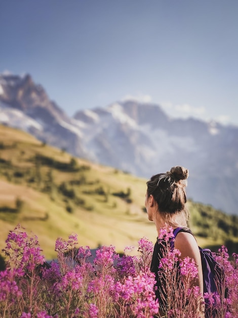 Foto mujer mirando hacia otro lado mientras está de pie en medio de plantas con flores