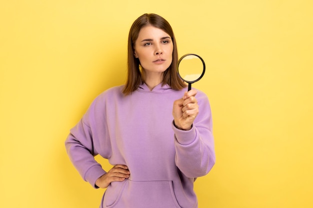 Mujer mirando hacia otro lado a través de una lupa espiando descubriendo algo explorando la escena del crimen