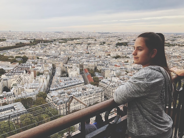 Foto mujer mirando el paisaje urbano contra el cielo