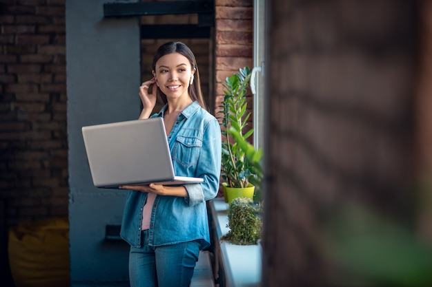 Mujer mirando la pantalla del portátil mientras usa auriculares inalámbricos