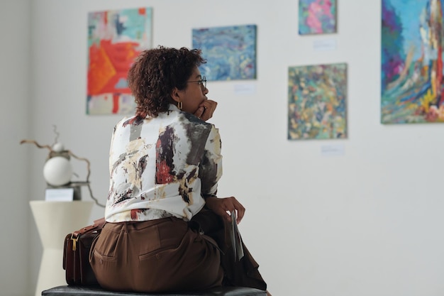 Mujer mirando pinturas en la pared.