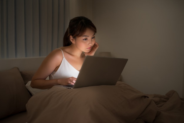 Mujer mirando portátil en la cama