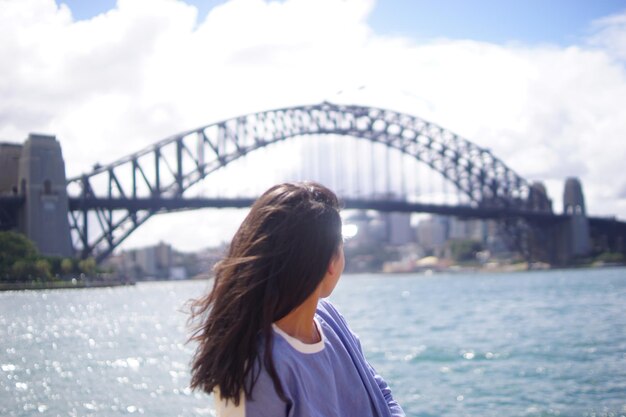 Foto mujer mirando el puente de arco sobre el río