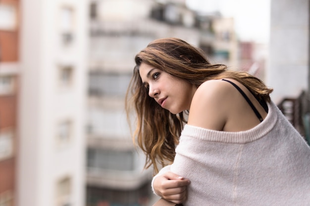 Foto mujer mirando desde su balcón la ciudad