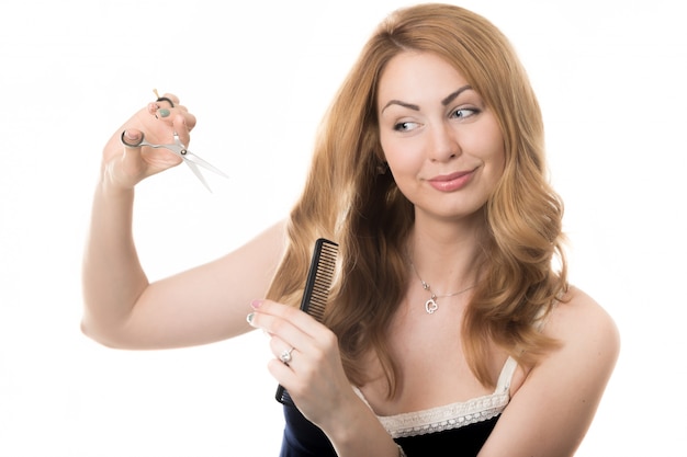 Mujer mirando su pelo con unas tijeras en sus manos