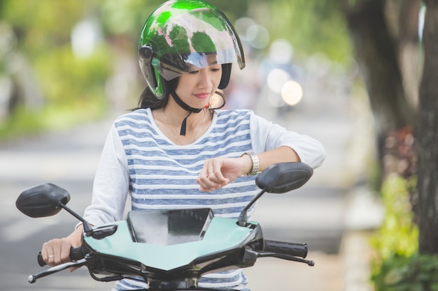 Mujer mirando su reloj mientras viajaba en moto en la calle