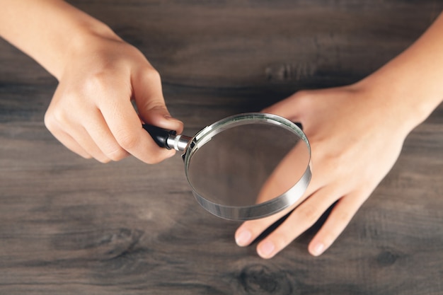 Mujer mirando sus uñas con una lupa