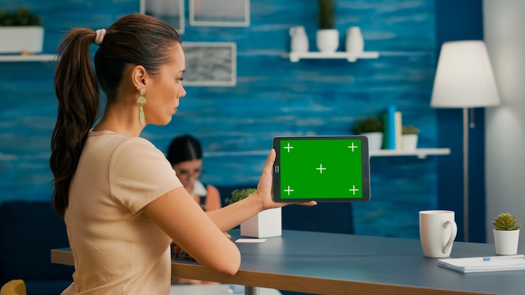 Foto mujer mirando tablet pc con simulacro de pantalla verde chroma key navegando en internet buscando ideas de estilo de vida. freelancer con dispositivo aislado de pie en la oficina de escritorio en la sala de estar