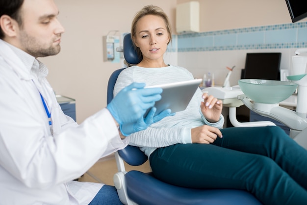 Mujer mirando tableta con médico dentista