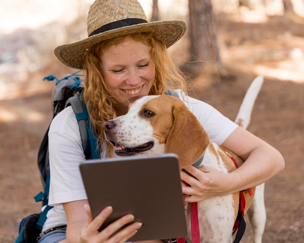 Mujer mirando la tableta y sosteniendo a su perro
