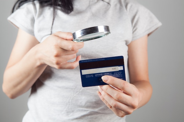 Mujer mirando una tarjeta bancaria con una lupa