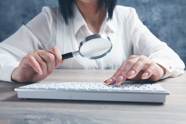 Foto mujer mirando el teclado con una lupa