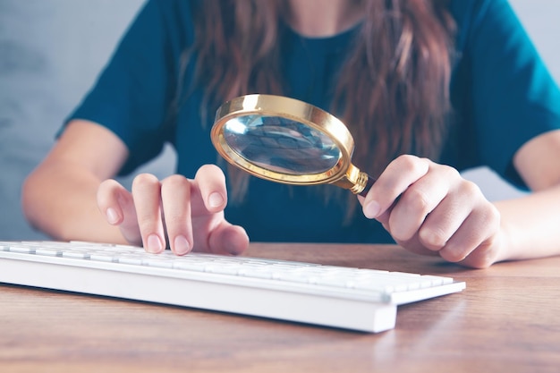 Mujer mirando el teclado con una lupa