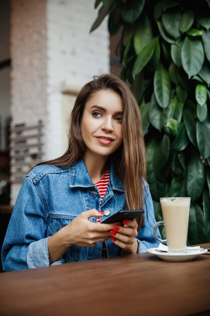 Mujer mirando el teléfono en una cafetería.