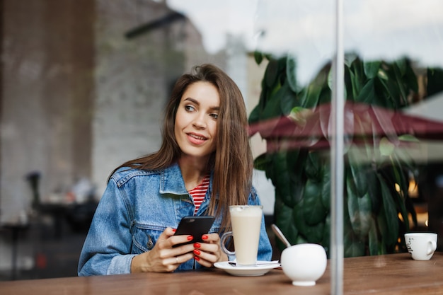 Mujer mirando el teléfono en una cafetería.