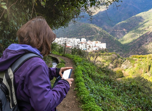 Mujer mirando el teléfono celular cerca de un pueblo blanco en andalucia españa