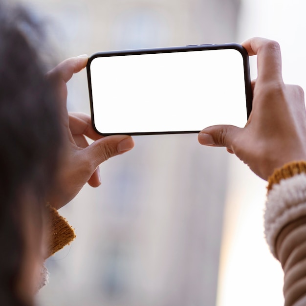 Mujer mirando un teléfono inteligente de pantalla vacía