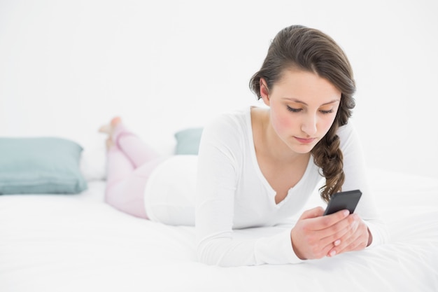 Mujer mirando el teléfono móvil en la cama