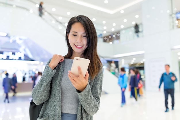 Mujer mirando por teléfono móvil en un centro comercial