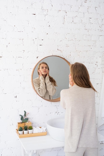 Mujer mirándose al espejo maquillándose por la mañana