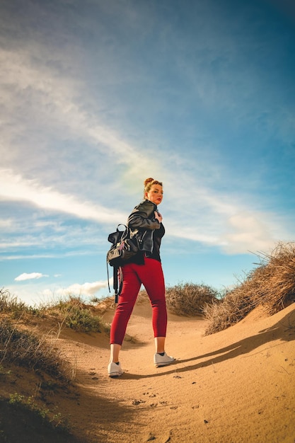 Foto mujer con mochila caminando sobre la arena en las dunas del desierto en una brillante foto de verano de alta calidad