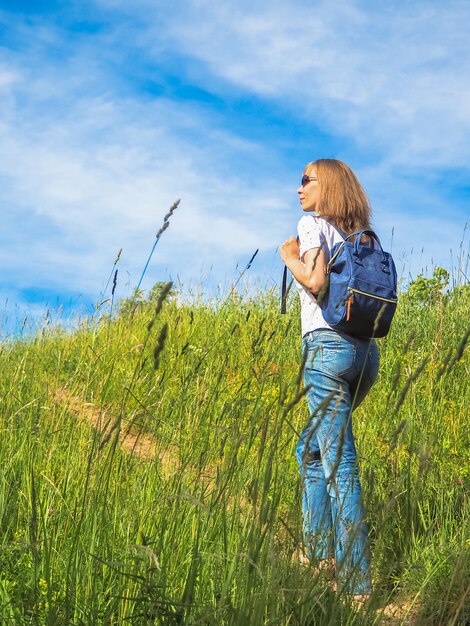 Mujer con mochila caminando sobre una colina